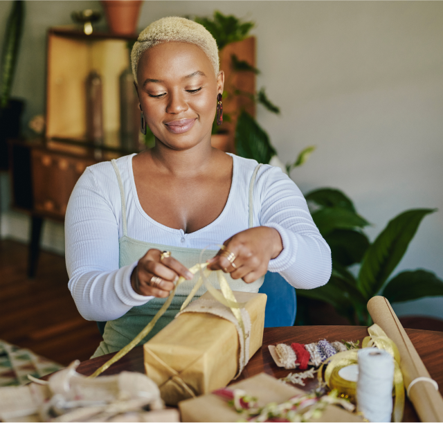 Woman wrapping gift at her dining table.